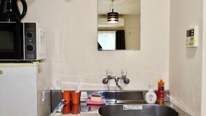 A kitchen with a microwave, sink, and a small window above the sink.