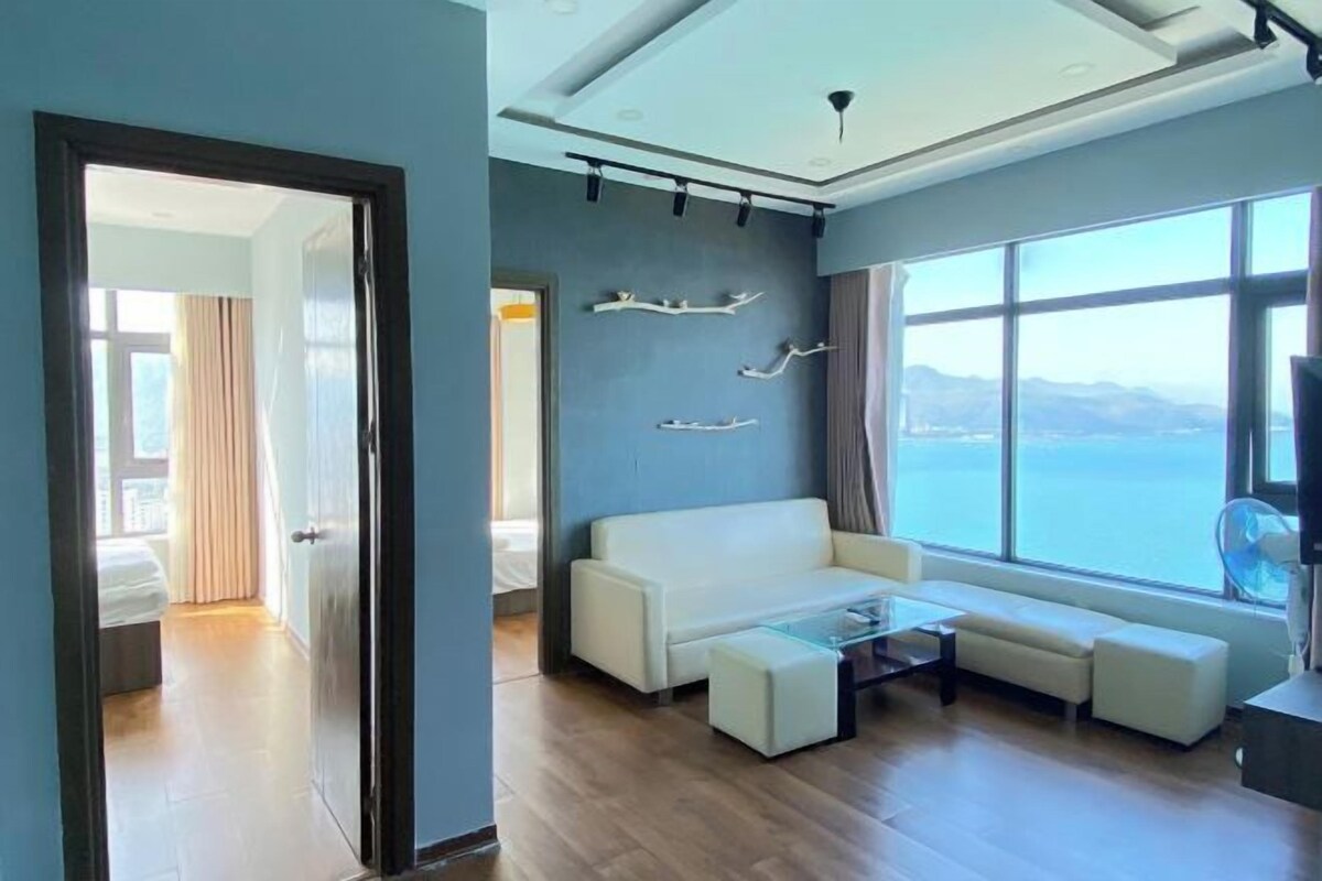A modern living room with a sofa, a coffee table, and a view of the sea.