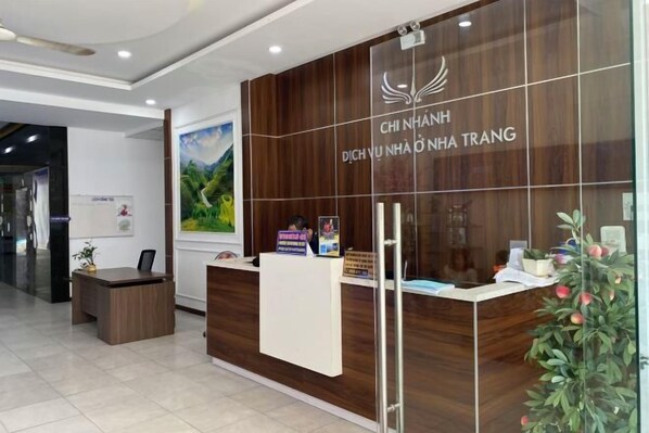 A reception desk with a wooden panel design, a logo, and a sign indicating a 40% discount. - Muong Thanh Hon Chong Apartment with Sea View (Nha Trang)