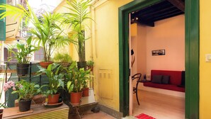 A small, cozy room with a red sofa and a green door. There are several potted plants outside the door. - Rental in Rome Campo De Fiori Apartment (Rome)