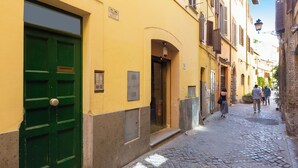 A narrow cobblestone street with a green door and yellow walls. - Rental in Rome Campo De Fiori Apartment (Rome)