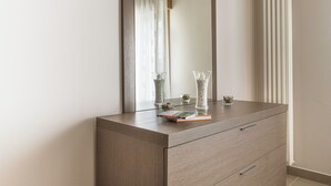 A wooden dresser with a mirror, two glass vases with white pebbles, and a book. - Apt Wanderlust 1 with swimming pool[Unesco-Prosecco] (Bagnolo)