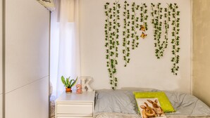 A bedroom with a bed, a nightstand, a dresser, a window with curtains, and green vines on the wall. - 'Irlulan' Apartment with Private Terrace and Wi-Fi (Platja d'Aro)