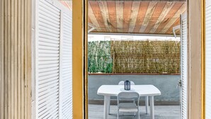 An open doorway leading to a patio with a white table and chairs, a bamboo fence, and a wooden ceiling. - 'Irlulan' Apartment with Private Terrace and Wi-Fi (Platja d'Aro)