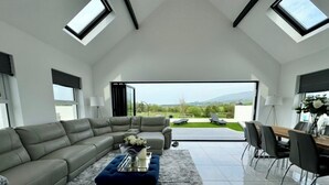 Ein modernes Wohnzimmer mit einer Eckcouch, einem Couchtisch und einem Essbereich mit Stühlen.