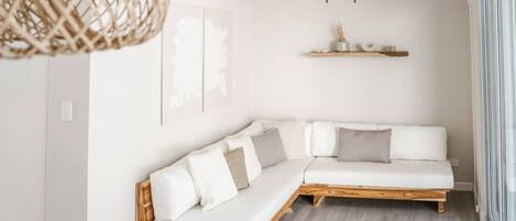 A modern living room with a white sectional sofa, a ceiling fan, and a wall-mounted air conditioner.