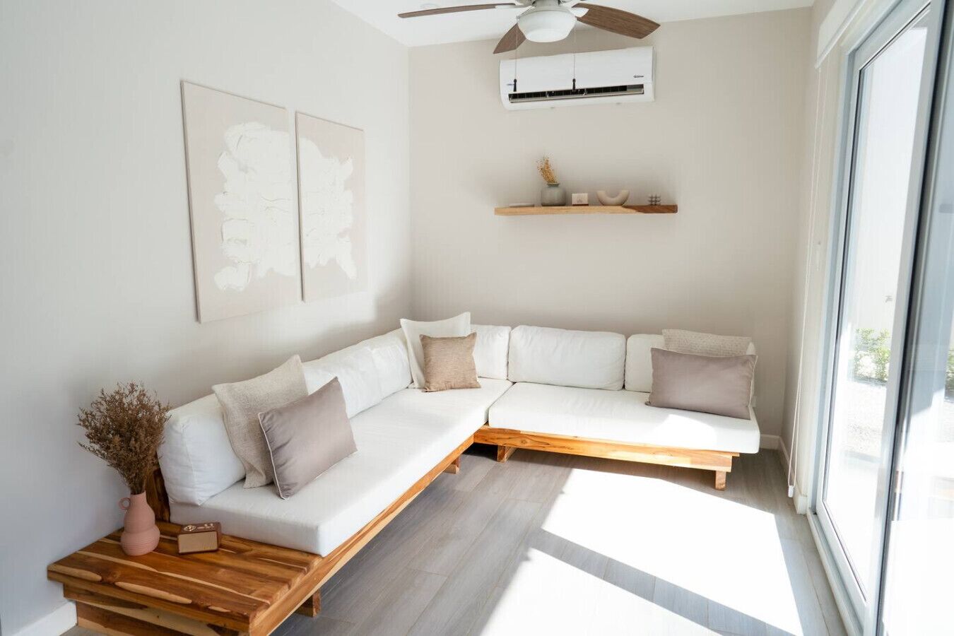 A modern living room with a white sectional sofa, wooden coffee table, and a ceiling fan.