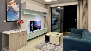 Un salon moderne avec un téléviseur à écran plat, un canapé, une table basse et un meuble.