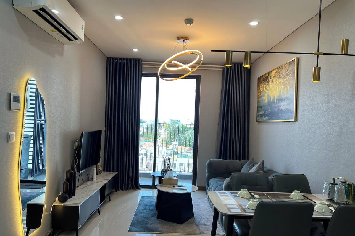 Un salon moderne doté d’un téléviseur à écran plat, d’un canapé, d’une table à manger et d’un balcon offrant une vue agréable.