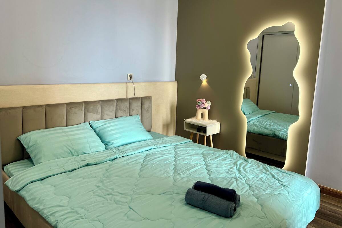 Une chambre à coucher avec un lit, une table de chevet avec une lampe et un miroir.