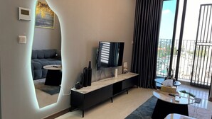 Un salon moderne avec un canapé, un téléviseur, une console et un grand miroir.