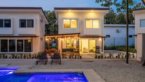 A modern two-story house with a covered patio and a swimming pool.