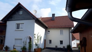 Un immeuble résidentiel de deux étages, doté d’une antenne parabolique, d’une cheminée et d’une allée pavée.