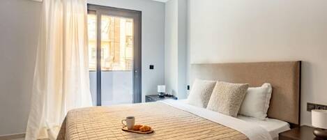 Habitación de hotel con cama, mesita de noche, una silla, ventana con cortinas y vista al exterior.