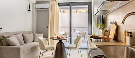 A modern kitchen with a dining area, a sofa, and a large window.
