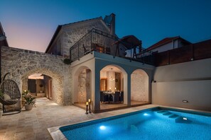 Un bâtiment en pierre doté d’une piscine, d’un balcon et d’un espace repas.