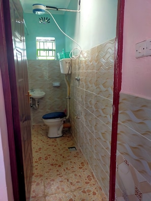 A small bathroom with a toilet, sink, and a shower area.