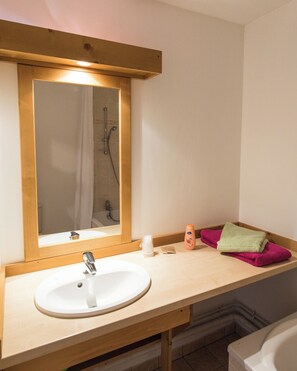 Une salle de bain avec un meuble-lavabo en bois, un évier, un miroir et une douche.
