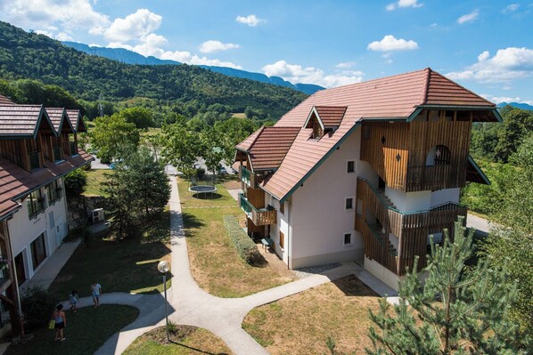 Un complexe hôtelier comprenant plusieurs bâtiments en bois, un chemin principal et un paysage montagneux en arrière-plan.