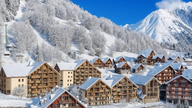 A snow-covered mountain resort with wooden chalets and a ski slope.