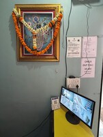 Quarto com pintura religiosa emoldurada, uma câmera de segurança e um monitor exibindo imagens de vigilância.