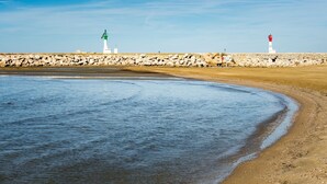 Un paysage côtier avec un phare, une côte rocheuse et une eau calme.