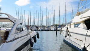 Un port de plaisance où sont amarrés plusieurs bateaux, avec une surface d’eau calme et un ciel dégagé.