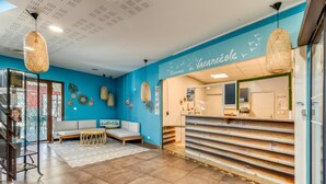 Un espace d’accueil avec un mur bleu, un comptoir de réception, un canapé et un luminaire suspendu.