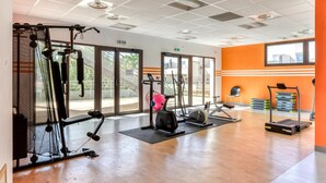 A gym with cardio machines, weightlifting equipment, and a large window providing natural light. - Résidence Cap Camargue 3P6C (Le Grau-du-Roi)