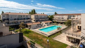 A residential building with a swimming pool, balconies, and a clear sky. - Résidence Cap Camargue 3P6C (Le Grau-du-Roi)