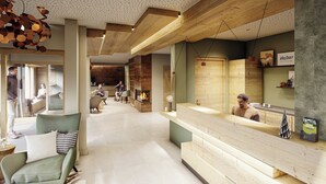 A modern hotel lobby with a reception desk, seating area, and a fireplace.