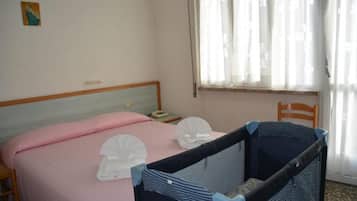 Una camera da letto con un letto, una culla, un comodino e una finestra con tende.