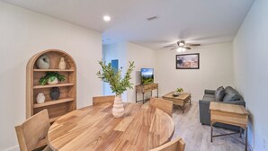 Ein modernes Wohnzimmer mit einem runden Holzesstisch, einer Couch und einem Fernseher.
