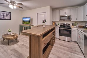 Une cuisine moderne dotée d’un îlot central en bois, d’appareils électroménagers en acier inoxydable et de meubles de couleur claire.