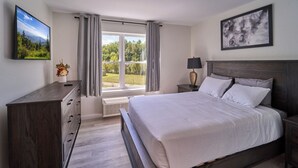 A bedroom with a large bed, a dresser, a nightstand, a TV, and a window with curtains. - Ruby 306: 1BD | Great LOCATION + Shared Amenities! (Pigeon Forge)