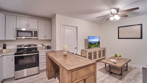 A modern kitchen with white cabinets, stainless steel appliances, a wooden island, and a ceiling fan. - Ruby 306: 1BD | Great LOCATION + Shared Amenities! (Pigeon Forge)