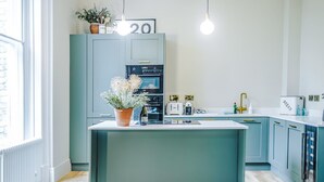 Uma cozinha moderna com ilha central, forno embutido e geladeira.
