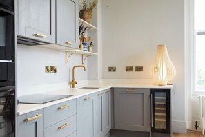 A modern kitchen with grey cabinets, a white countertop, and a built-in oven. - Railway House -Platform 6, 2 Bedroom Apartment. (York)
