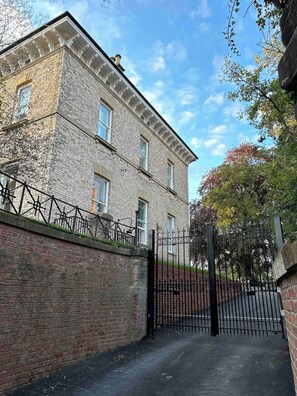 A brick building with a gated entrance, a brick wall, and a clear sky. - Railway House -Platform 6, 2 Bedroom Apartment. (York)