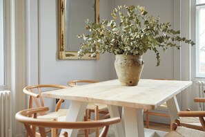 A dining area with a wooden table and chairs, a potted plant, and a mirror on the wall. - Railway House -Platform 6, 2 Bedroom Apartment. (York)