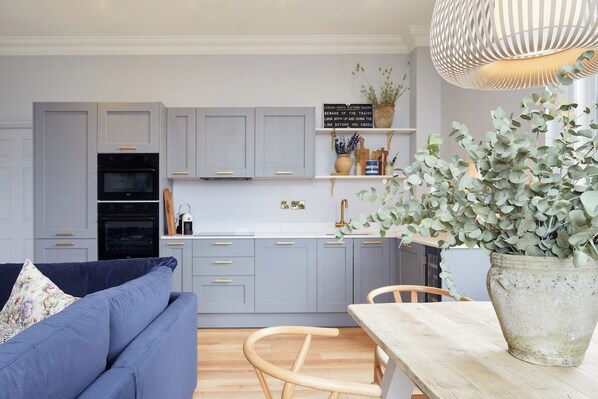 Una cocina moderna con armarios grises, horno negro y una mesa de comedor de madera.