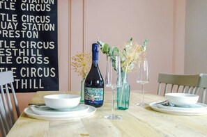A table set with a bottle, glasses, and bowls, with a sign in the background.
