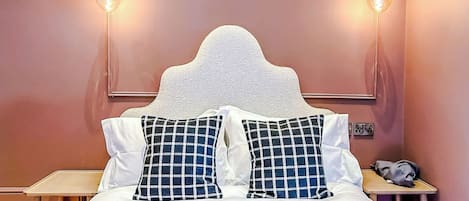 A bed with a white headboard, two pillows with a checkered pattern, and two wall-mounted light fixtures.