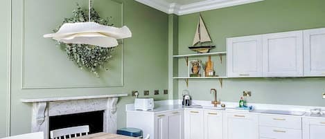 A kitchen with white cabinets, a wooden dining table, and a hanging light fixture.