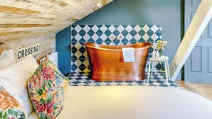 Quarto com uma banheira grande, teto de madeira e parede revestida com um padrão geométrico.
