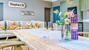 Uma sala de estar moderna com sofá, mesa de jantar com cadeiras, área de cozinha e placas de sinalização na parede.