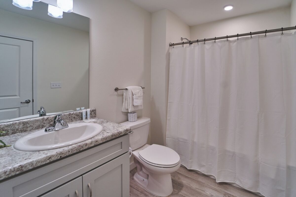 A bathroom with a white sink, toilet, and shower curtain.