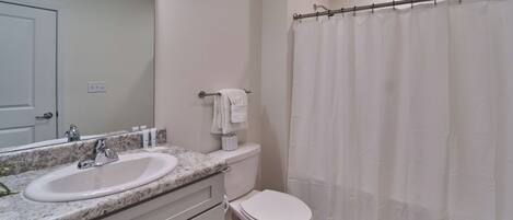 A bathroom with a white sink, toilet, and shower curtain.