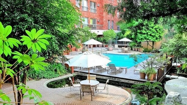 Uma área de piscina com um deque circular, espreguiçadeiras e guarda-sóis.