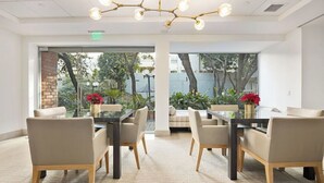 Uma sala de conferências com mesas de vidro, cadeiras bege e um lustre moderno.